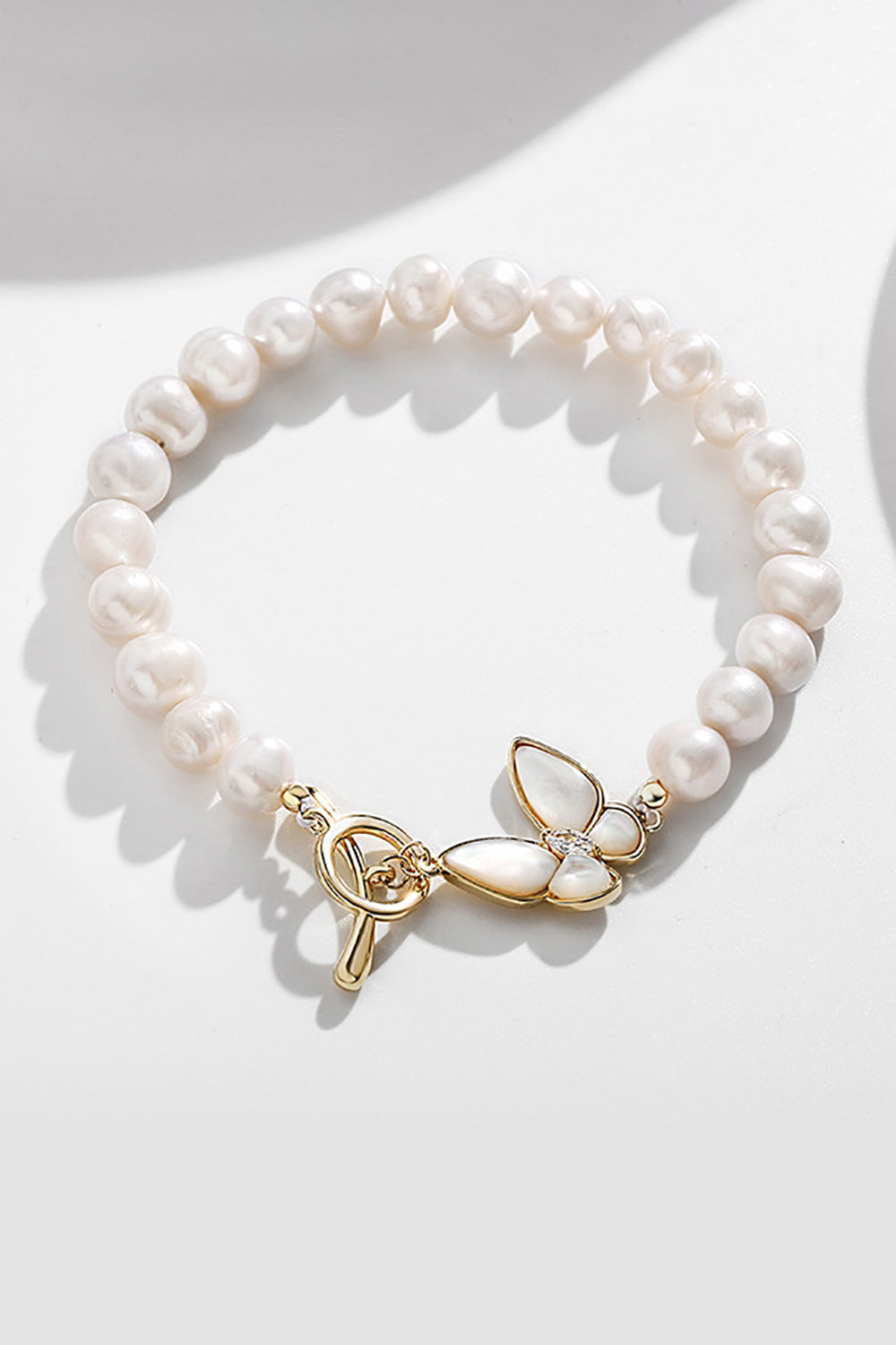 Glitrende hvidt perle stretch armbånd med sommerfugl