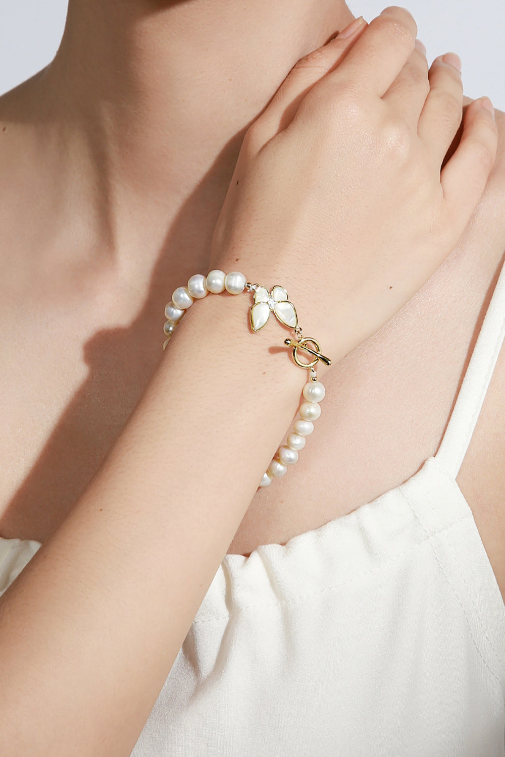 Glitrende hvidt perle stretch armbånd med sommerfugl