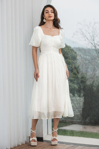 En linje plisseret lille hvid kjole med pufærmer